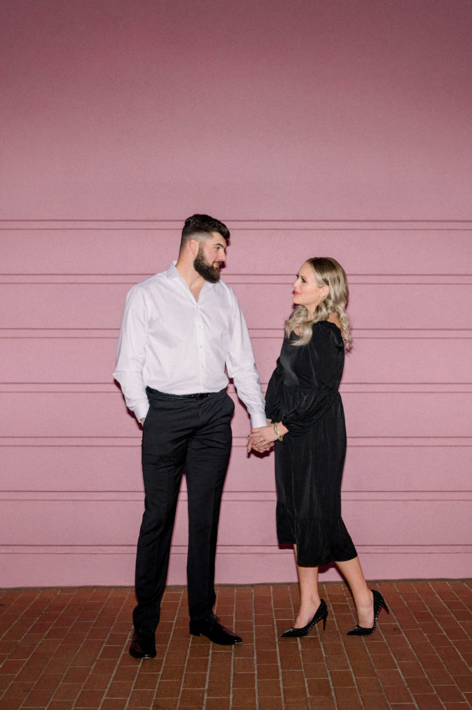 guy and girl standing in front of pink wall