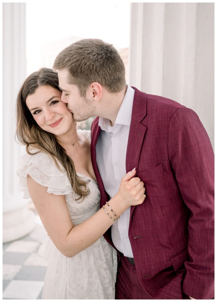 couple hugging and kissing on the porch of hibernian Hall in charleston south carolina