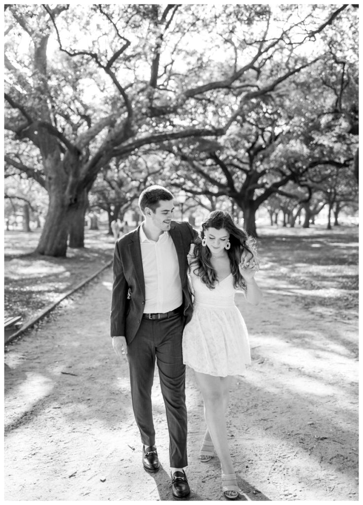 man walking with arm around woman in white part gardens in charleston south carolina engagement session