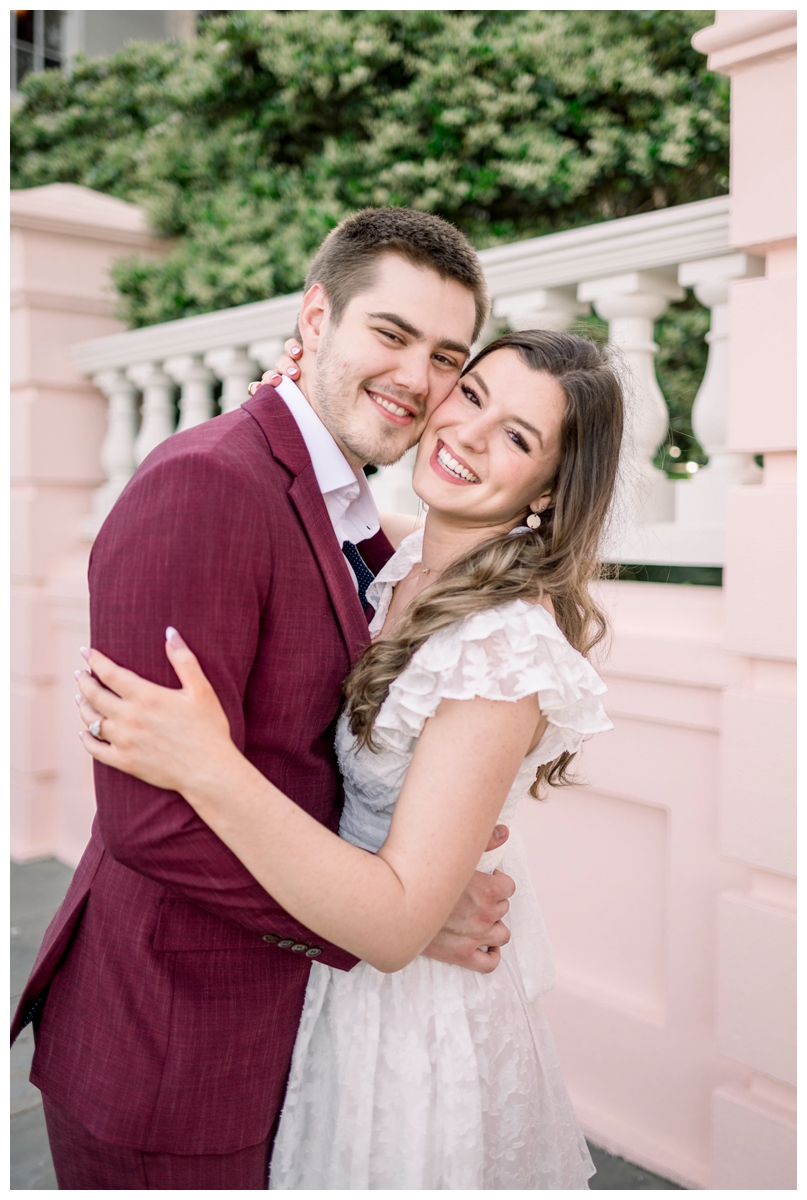 couple standing in front of pink and white wall in charleston south carolina