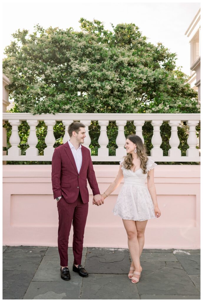 couple standing in front of white and pink wall in downtown charleston south carolina