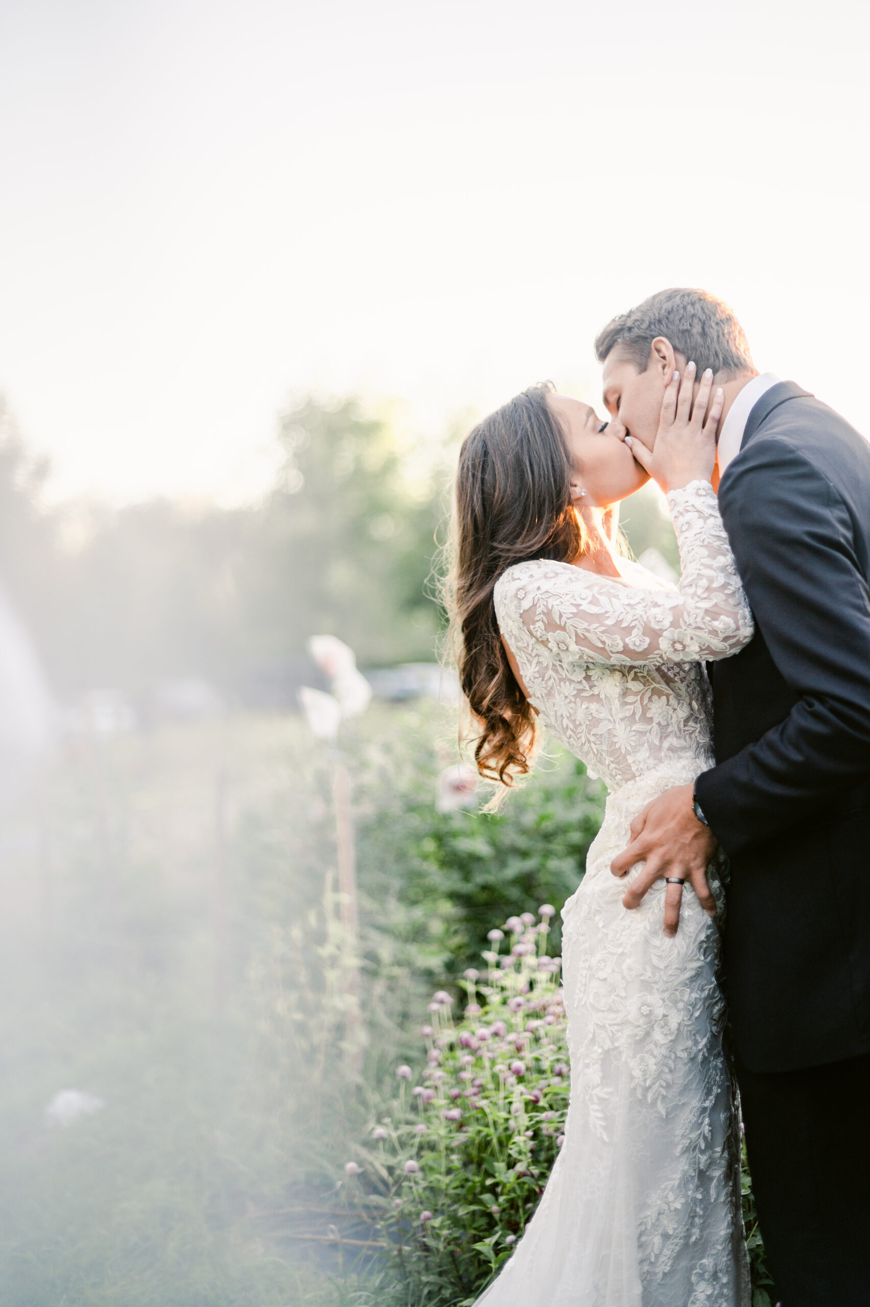 bride and groom in front of flower field kissing